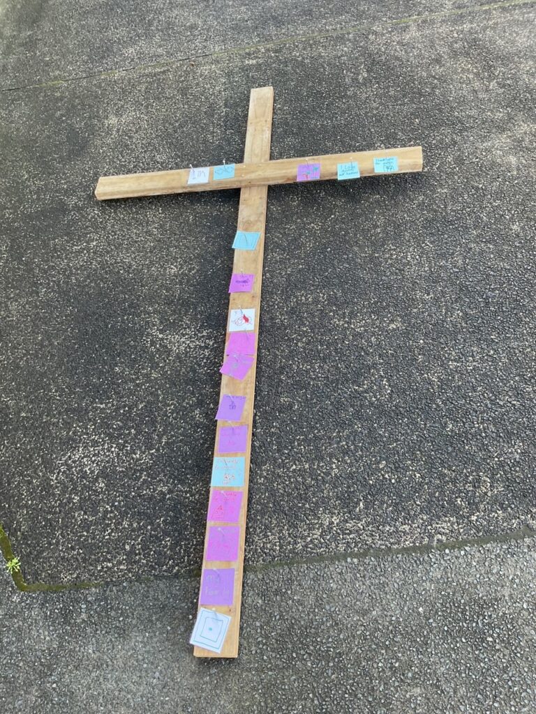 Wooden cross with messages attached.