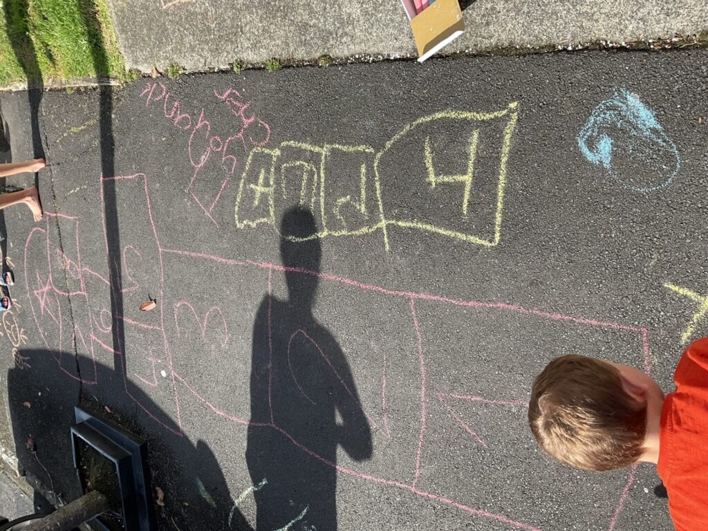 Children looking at hopscotch chalked on the pavement.