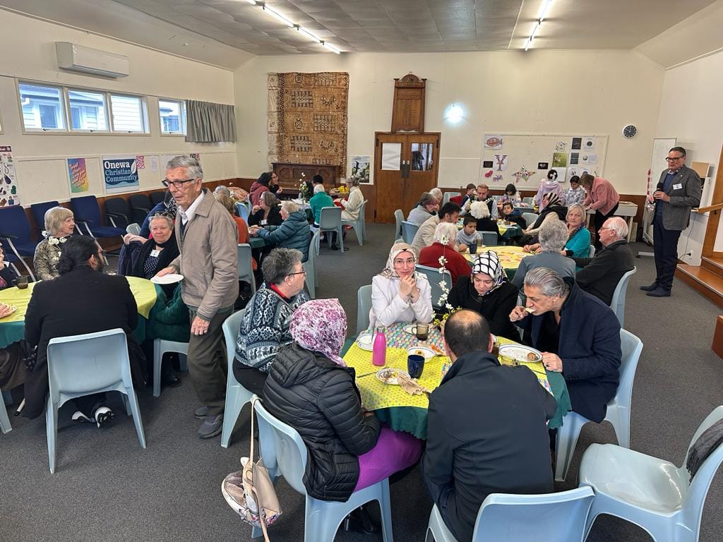 Tables of people sharing breakfast. Some women are wearing a hijab.