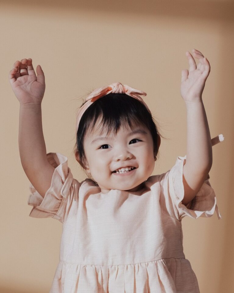 Little girl with her arms in the air. Possibly dancing to music.